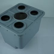 Top view of a pale blue plastic device with five circular holes: one large central hole and four smaller surrounding ports, seen from above.